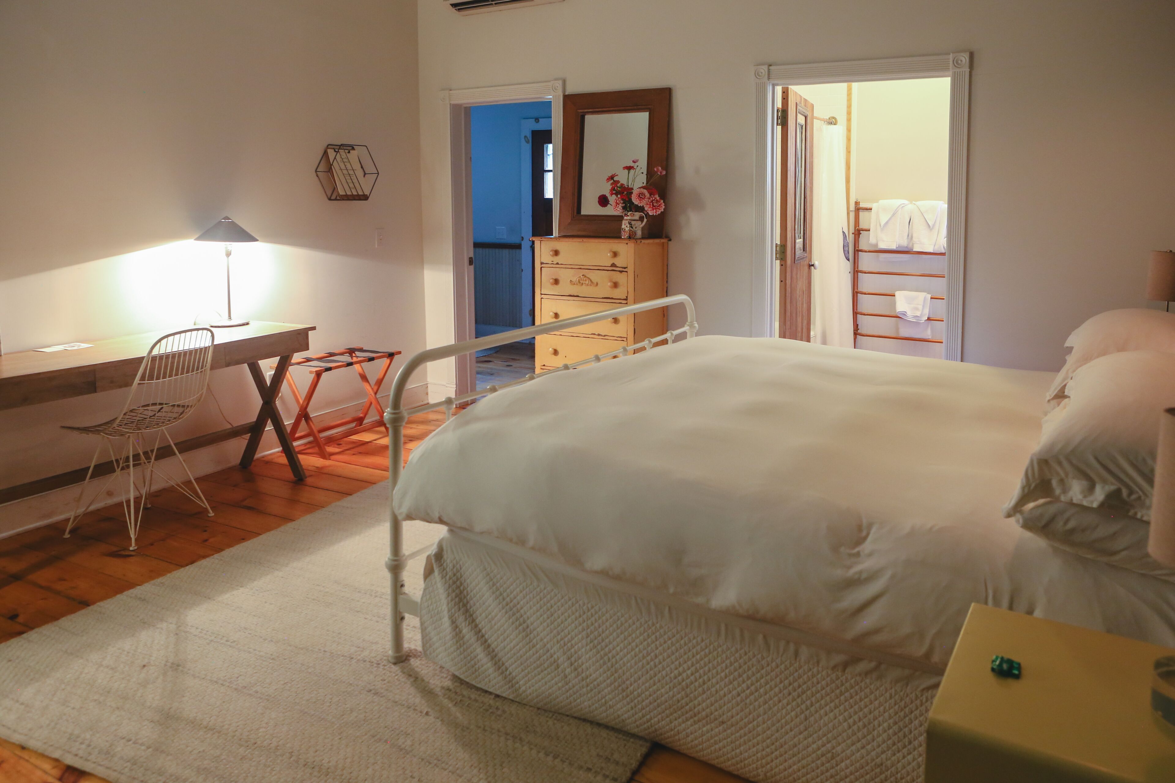 Quarto com cama, escrivaninha, cadeira, cômoda e espelho.