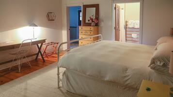 Quarto com cama, escrivaninha, cadeira, cômoda e espelho.
