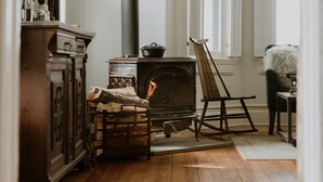 A cozy room with a wood-burning stove, a rocking chair, and a fireplace. - The North Branch Inn (North Branch)