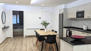 A modern kitchen with a dining area, featuring a wooden table, black chairs, and a potted plant. - Hydros Freser Ripoll (Ripoll)