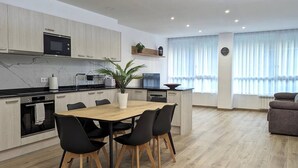 A modern kitchen with a dining area, wooden cabinets, a microwave, and a potted plant. - Hydros Freser Ripoll (Ripoll)