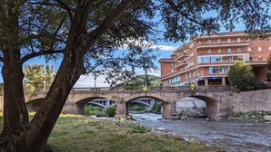 A stone bridge over a river with a building in the background. - Hydros Freser Ripoll (Ripoll)