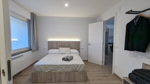 A modern bedroom with a bed, a bedside table, a wardrobe, and a view of a hallway. - Hydros Freser Ripoll (Ripoll)