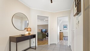 A modern interior with a round mirror, a desk, a green sofa, and a television in the background. - Bahnhofstraße 10 - Wohnung 4 - Moderne und Familienfreundliche Ferienwohnung in Zentrumsnähe (Zingst)