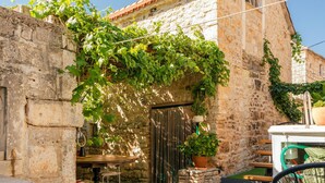 A stone building with a rustic charm, featuring a wooden table and chairs outside, a potted plant, and a clear blue sky in the background. - Stunning home in Donje Selo (Donje Selo)