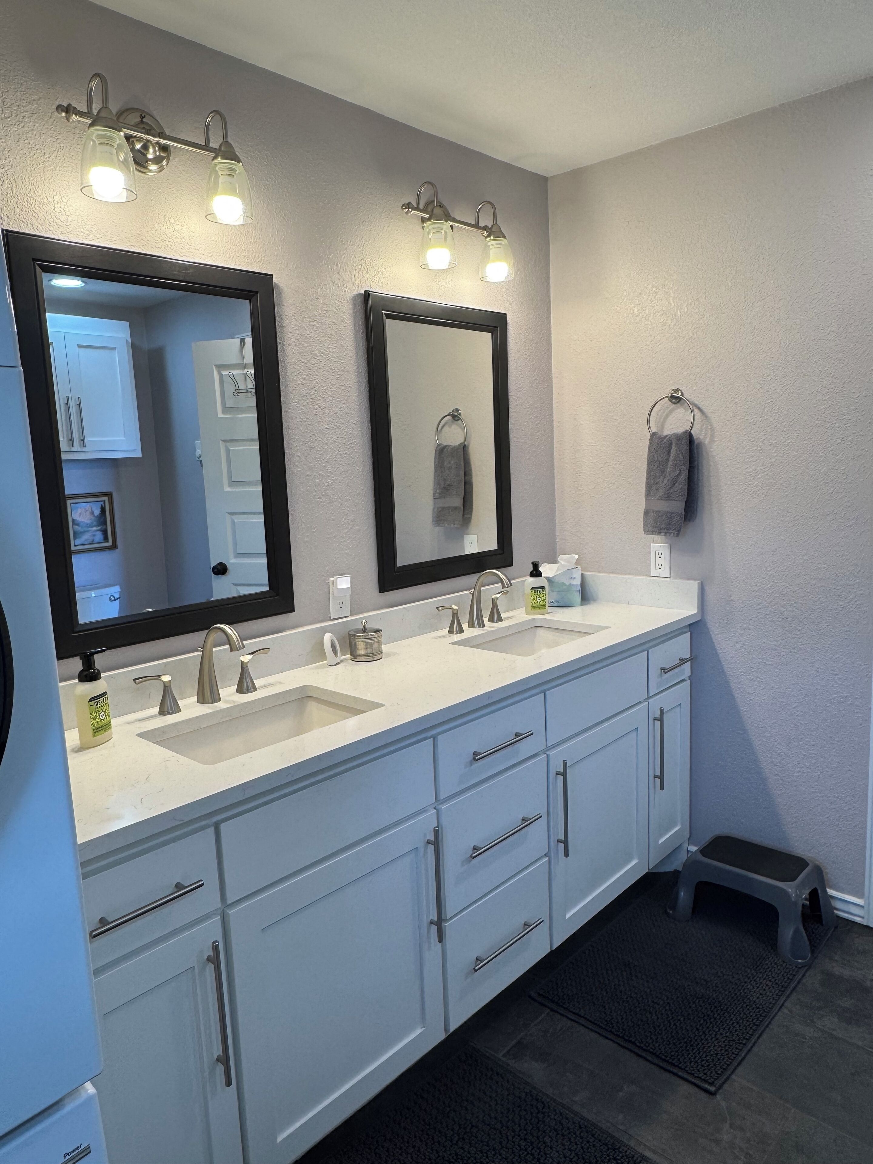 A bathroom with two sinks, a large mirror, and a towel rack.