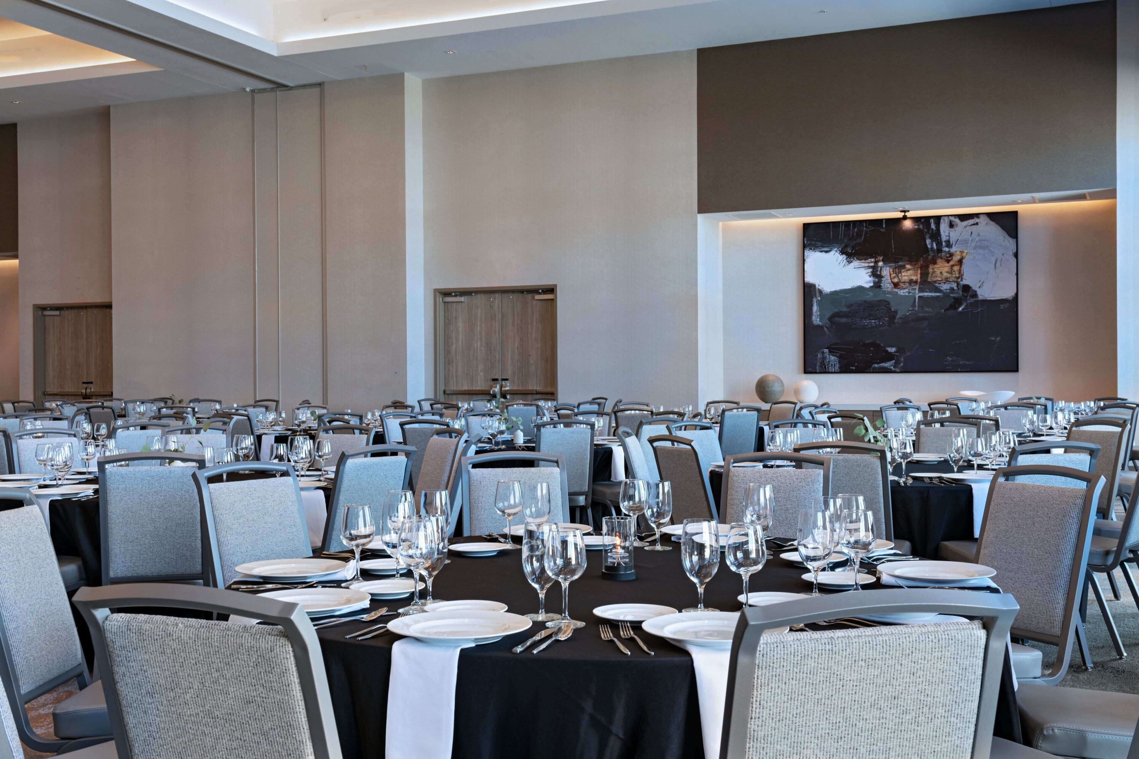 A conference room with multiple tables set for dining, equipped with chairs, plates, and cutlery.