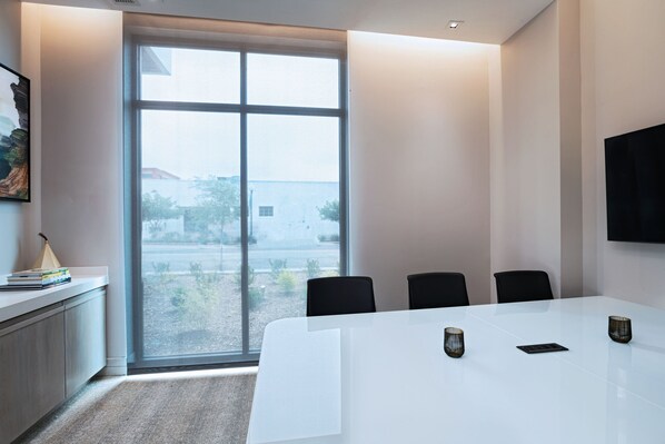 A conference room with a large table, four chairs, and a television on the wall. - AC Hotel By Marriott Waco Downtown (Waco)