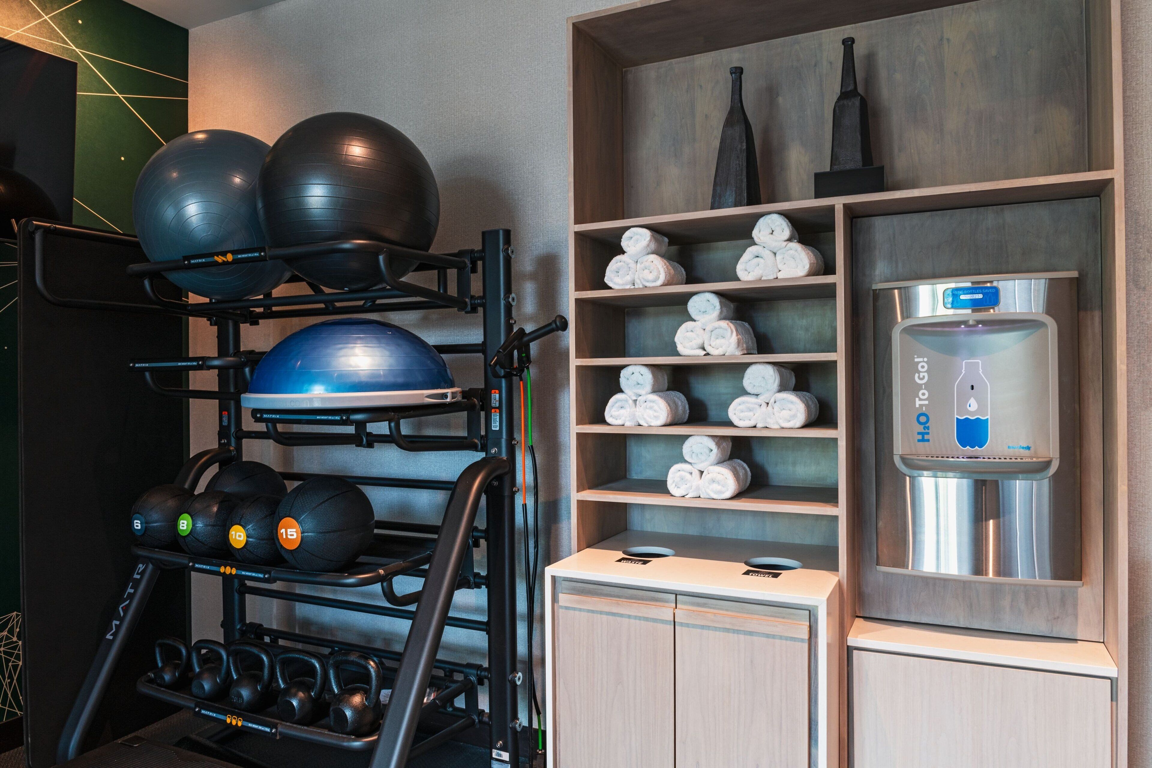 A gym with exercise equipment, towels, and a water dispenser.