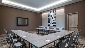 A conference room with a long table, chairs, a large mirror, and a wall with a geometric pattern.