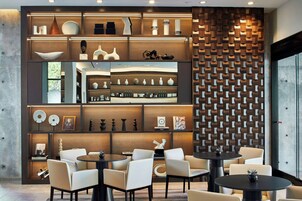 A modern interior with a central seating area, a decorative wall with geometric patterns, and shelves displaying various items.