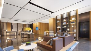 A modern lobby with a reception desk, seating area, and a bookshelf.