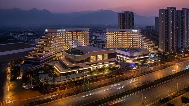 A hotel with multiple floors, a central courtyard, and a view of the surrounding cityscape and mountains.
