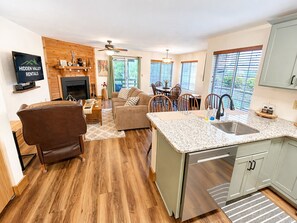 A modern kitchen with a granite countertop, a built-in sink, and a dining area with wooden chairs.