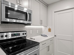 A modern kitchen with stainless steel appliances, white cabinetry, and a clean layout. - Chatham Crossing 2159 | 2 Living Rooms | Mtn View | Private Patio | Private Garage (Park City)