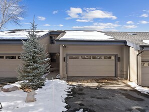A residential building with a garage, a snow-covered driveway, and a small evergreen tree. - Chatham Crossing 2159 | 2 Living Rooms | Mtn View | Private Patio | Private Garage (Park City)