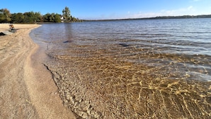 Un lac aux eaux limpides, bordé d’une plage de sable et agrémenté d’un banc.