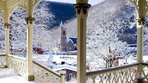 Un balcon enneigé offrant une vue sur une église et les arbres environnants.
