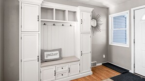 A room with a white built-in bench with storage drawers, a small seating area with a cushion, and a decorative mirror on the wall. - Buffalo Bliss - near Universities and natural areas-Large deck and backyard (Duluth)
