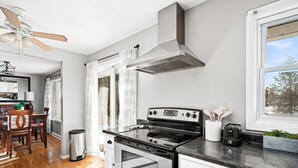A modern kitchen with a stainless steel stove, white cabinets, and a window with a view of trees. - Buffalo Bliss - near Universities and natural areas-Large deck and backyard (Duluth)