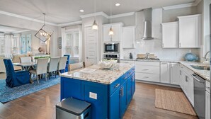 A modern kitchen with white cabinets, a blue island, and stainless steel appliances. - "Shore Beats Work" Large Inlet Beach Home - Bikes (Inlet Beach)