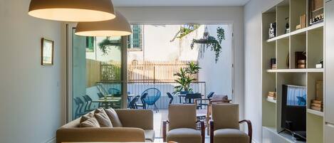 Uma sala de estar moderna com uma mesa de jantar de madeira, sofás bege e uma estante embutida para TV.