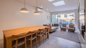 Een moderne eetruimte met een houten tafel en stoelen, een bank en uitzicht op het buitenlands landschap door grote ramen.