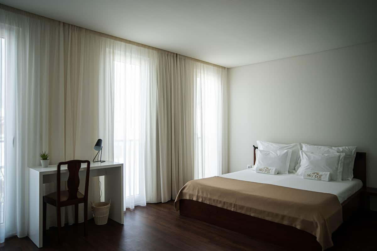 A bedroom with a bed, a desk, and a chair.