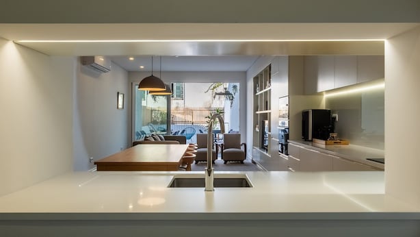 Een moderne keuken met een centraal kookeiland, inbouwapparatuur en een eethoek met een grote tafel en stoelen.