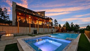 A modern house with a large swimming pool, a covered outdoor deck, and a stone wall. - The Overlook w/ Outdoor Pool, EV Outlet, Pickleball, Unbelievable Views (Broken Bow)