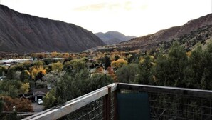A mountainous landscape with autumn foliage, a small building, and a fenced area.