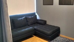 A dark-colored sectional sofa against a light-colored wall with two framed pictures. - Suite Zen con Jacuzzi y Terraza (Santiago de Querétaro)