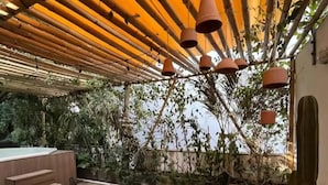 An outdoor patio with bamboo overhead structures, terracotta hanging lamps, and a variety of seating options including chairs and a table. - Suite Zen con Jacuzzi y Terraza (Santiago de Querétaro)