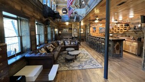 Een gezellig chaletinterieur met een leren bank, een barhoek en een rustieke inrichting.