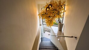 A modern staircase with a glass railing, a hanging light fixture, and a potted plant. - Hotel Boutique Veracruz (Santa Rosa de Cabal)