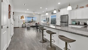 A modern kitchen with white cabinets, stainless steel appliances, and a central island with bar stools. - Bayfront Home, Shared Pool/Spa, Gazebo, Playground (Port Isabel)