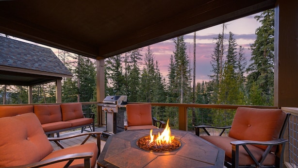 A deck with a fire pit, seating, and a grill.