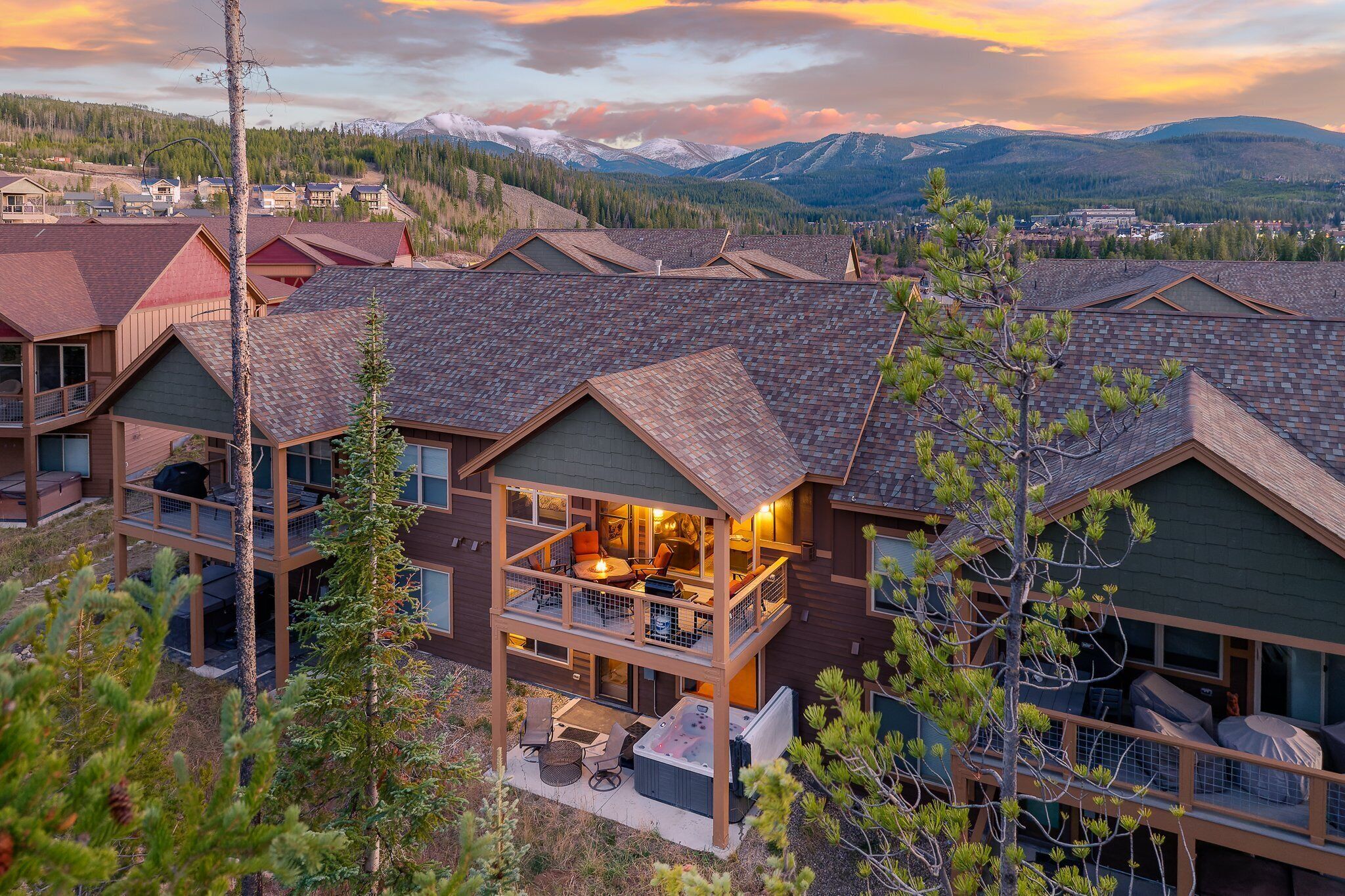 A multi-story lodge with a balcony, hot tub, and a view of mountains.