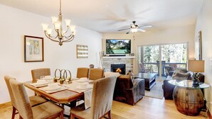 A spacious living area with a fireplace, a dining table set for six, and a comfortable seating arrangement.