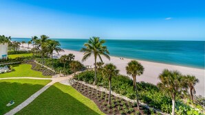 A beach view with palm trees, a clear sky, and a pathway leading to a building. - Get Ready for the Ultimate Beachfront Escape in Naples, Florida! (Naples)