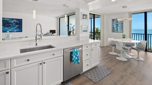 A modern kitchen with a large island, stainless steel appliances, and a view of the ocean. - Get Ready for the Ultimate Beachfront Escape in Naples, Florida! (Naples)