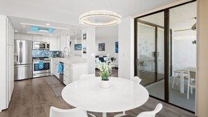 A modern kitchen with stainless steel appliances, a round dining table with chairs, and a chandelier. - Get Ready for the Ultimate Beachfront Escape in Naples, Florida! (Naples)