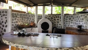 Zona cuina exterior amb paret de pedra, forn integrat i rentapeus.
