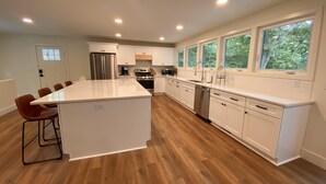 Una cocina moderna con armarios blancos, una isla grande y suelo de madera.