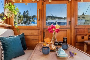 A wooden interior with a table set for breakfast, including pastries and a vase of flowers.