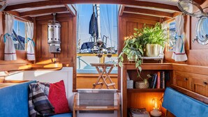 L’intérieur d’un chalet accueillant, avec un canapé bleu, des étagères en bois, une petite table et une plante en pot.