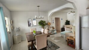 A spacious kitchen with a dining area, white walls, and a ceiling fan. - Villa vanel (West End)