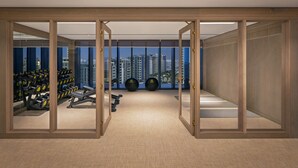Une salle de sport moderne, dotée d’équipements d’exercice, de grandes fenêtres et offrant une vue sur la ville.