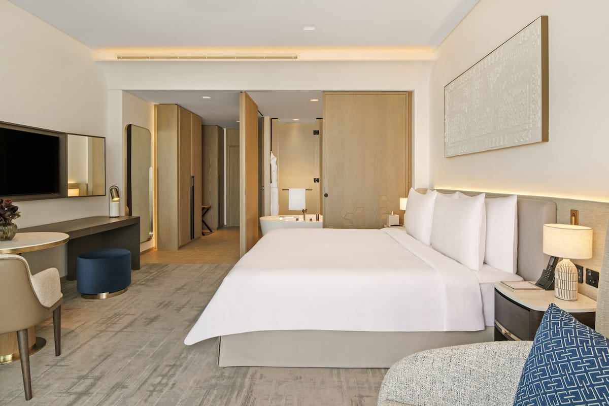 Een moderne hotelkamer met een groot bed, nachtkastjes, een bureau, een stoel en een televisie.