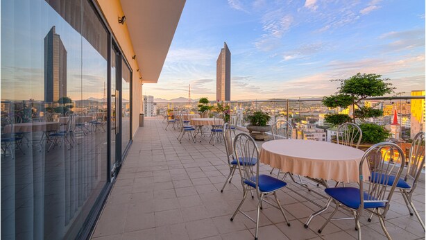 A rooftop terrace with tables and chairs, offering a city view. - AD41 HOTEL HUE CS1 (Hue)